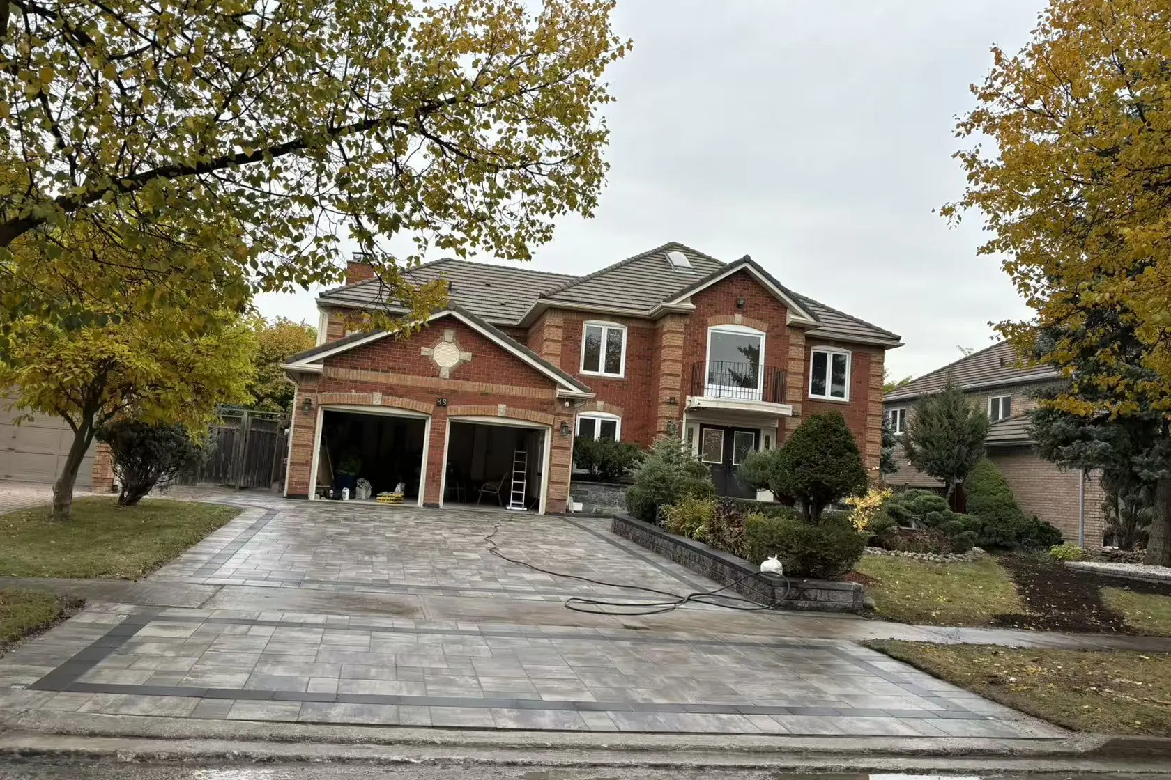 Grey interlock driveway -- large-format pavers, dark charcoal curved border, GTA brick home with double garage
