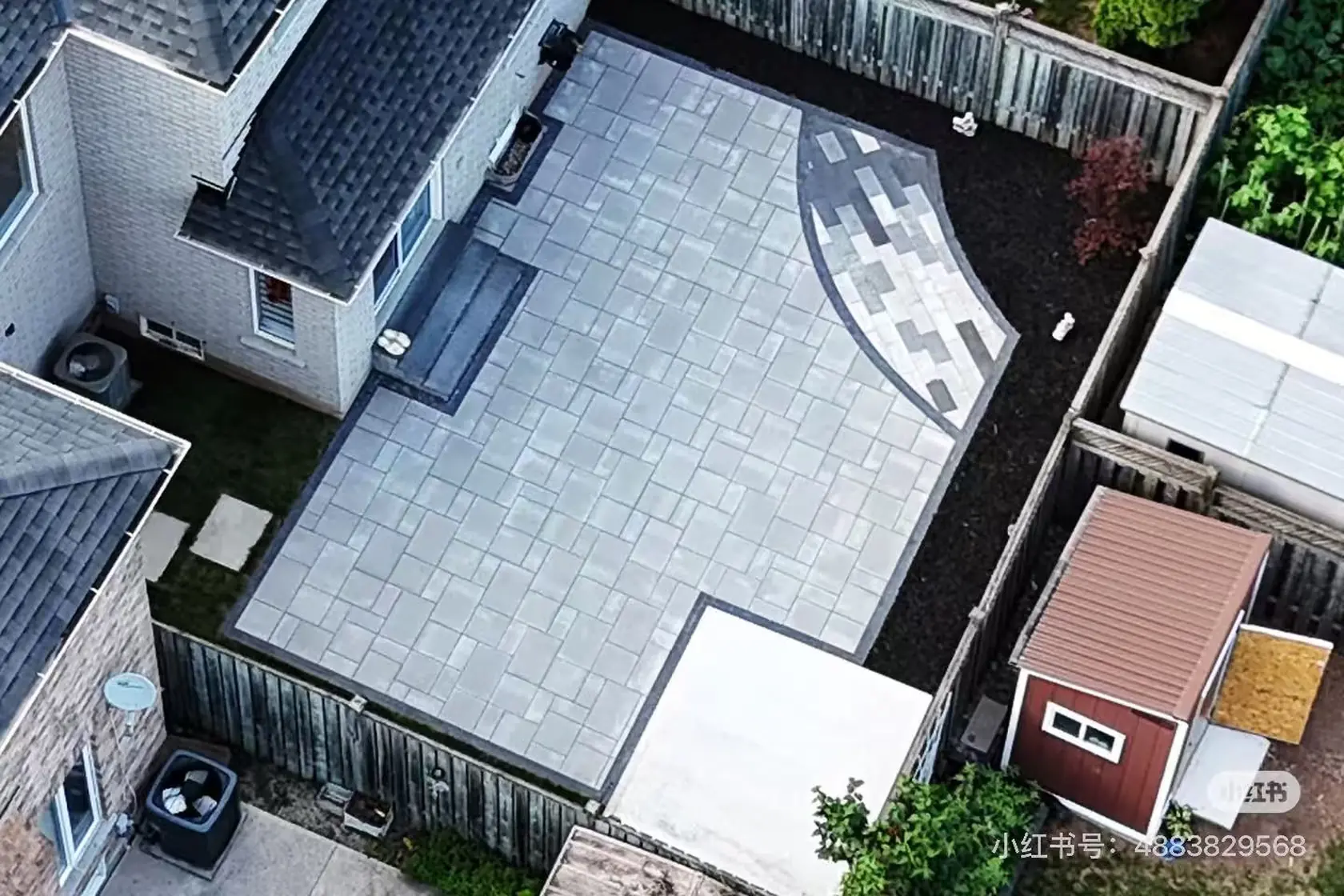 Grey interlock driveway -- large-format pavers, dark charcoal curved border, GTA brick home with double garage