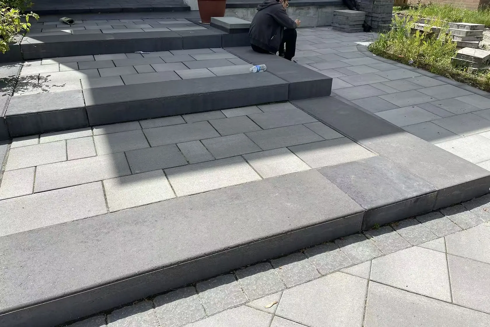 Grey interlock driveway -- large-format pavers, dark charcoal curved border, GTA brick home with double garage