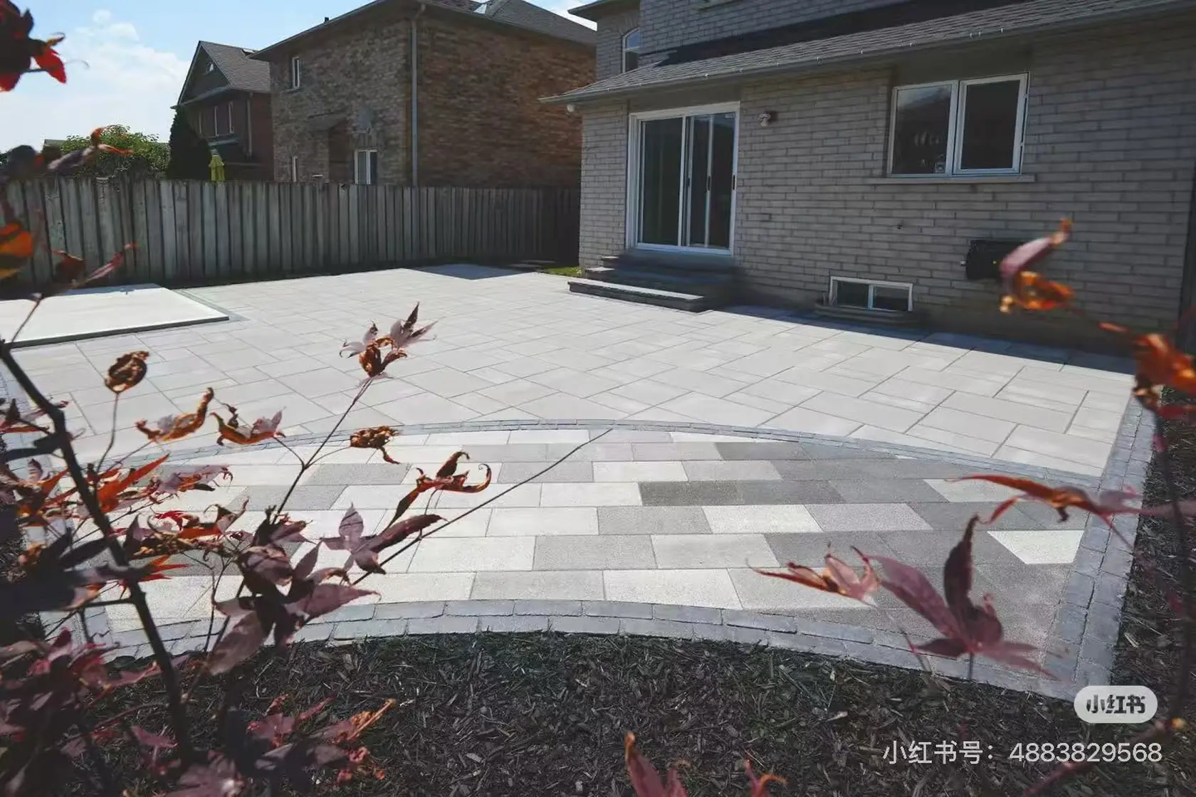 Grey interlock driveway -- large-format pavers, dark charcoal curved border, GTA brick home with double garage