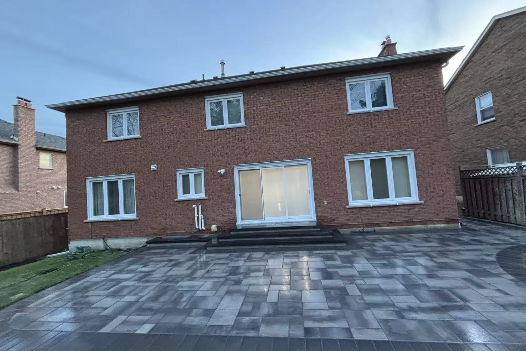 Grey interlock driveway -- large-format pavers, dark charcoal curved border, GTA brick home with double garage